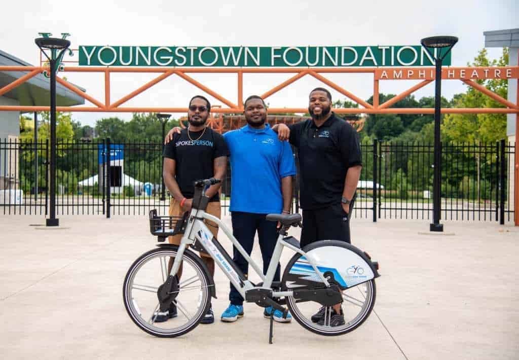 yogo bikeshare 3 male owners of a bikeshare stand with a bike in front of them
