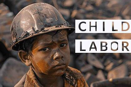 Young child in a construction helmet looking sad at a dirty construction site