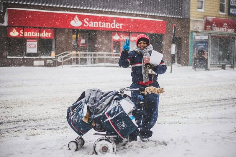 mailman snow victoria kubiaki Usps worker standing in the snow-covered street, waves and smiles
