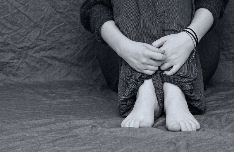 depressed black and white Ketamine treats people with major depressive disorder like this person, sitting on the floor with arms wrapped around their knees.