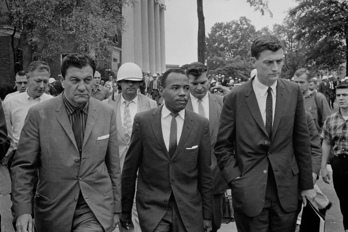 Photograph shows james meredith walking to class at ole missaccompanied by u. S. Marshals.