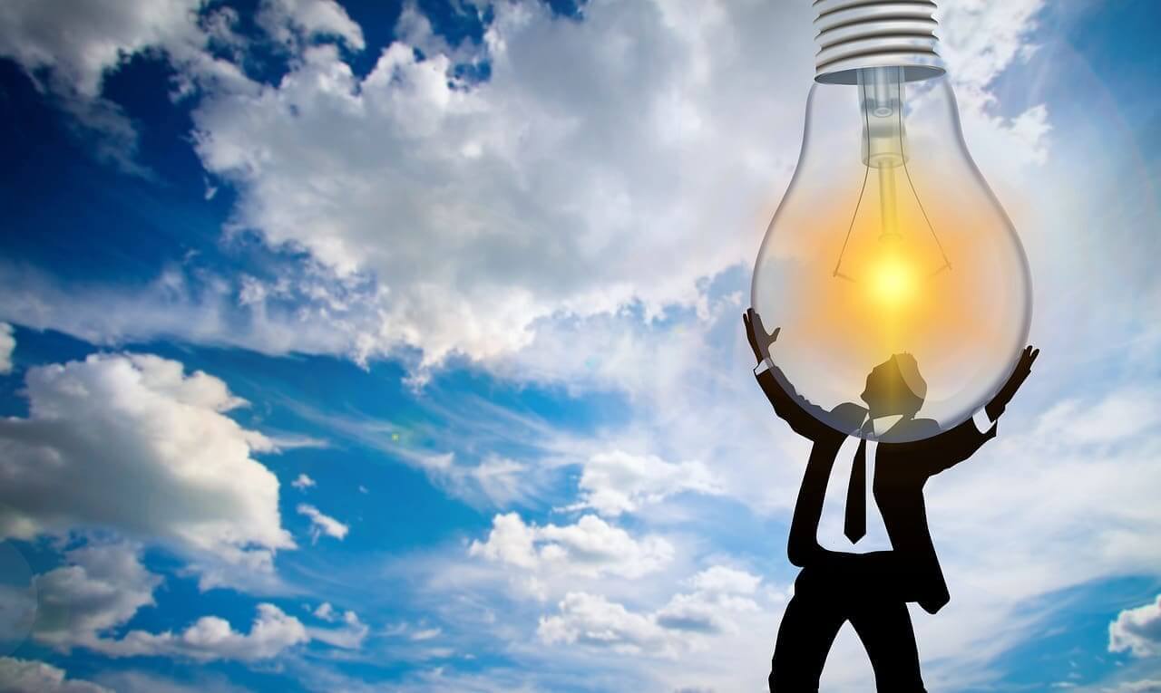 Ai data centers using energy consumers pay for. Blue sky with clouds, man in a suit is holding up a giant light bulb