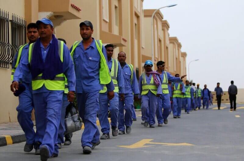 workers health1 Migrant workers walking in a single file line leaving work in qatar