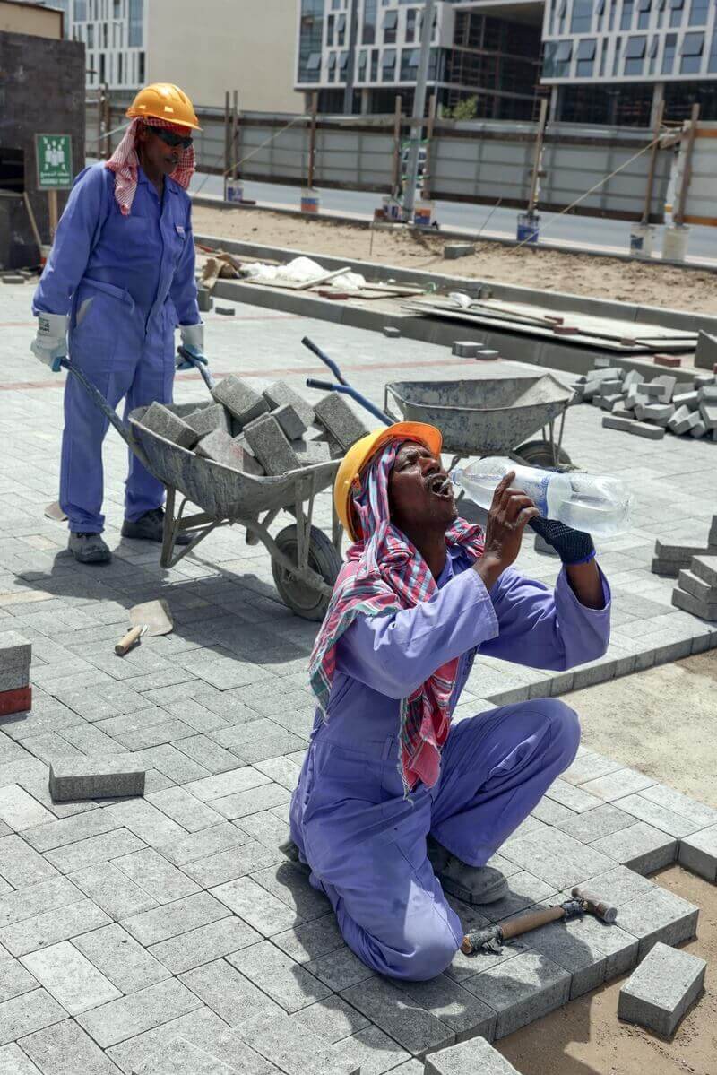 migrant worker gulping water Migrant workers laying concrete blocks. One is guzzling water.