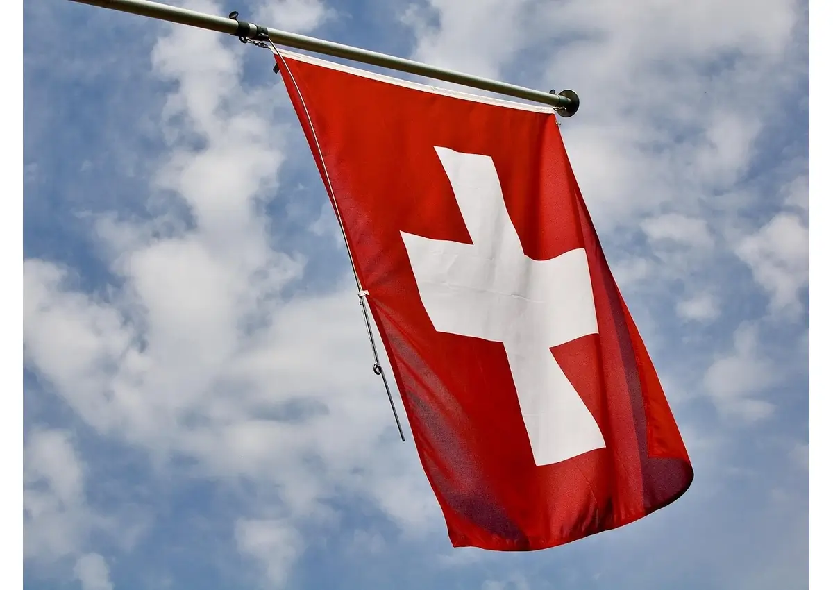 Flag of switzerland against a blue, cloudy sky