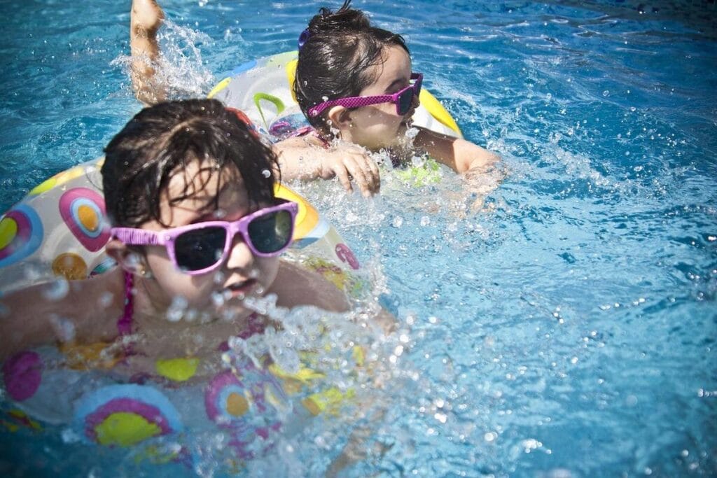 Girls on rafts in a swimming pool wearing sunglasses