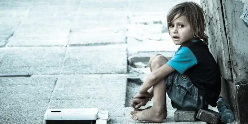 Trump to end tps for refugees from haiti and syria. A little syrian refugee sits on the street.