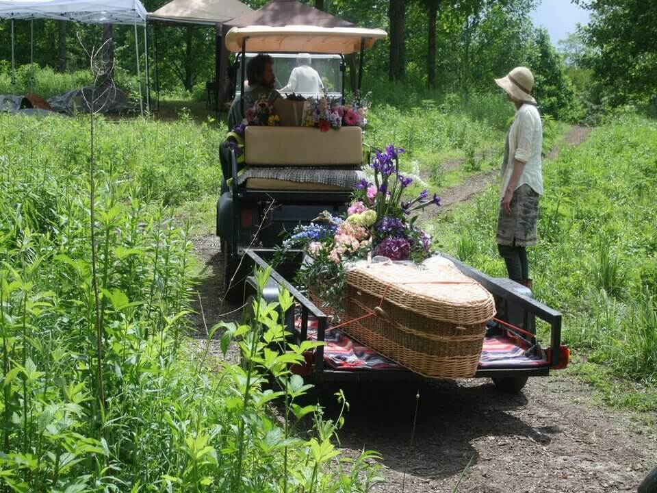 A wicked casket is transported to the green burial site.