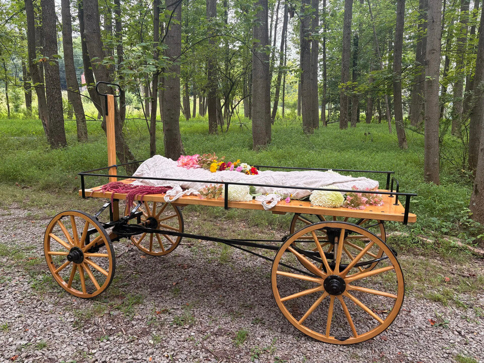 A green burial funeral service. The body is wrapped in a shroud and transported on a wooden wagon